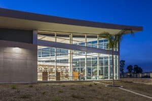 Glass-fronted civic library building lit from within at dusk